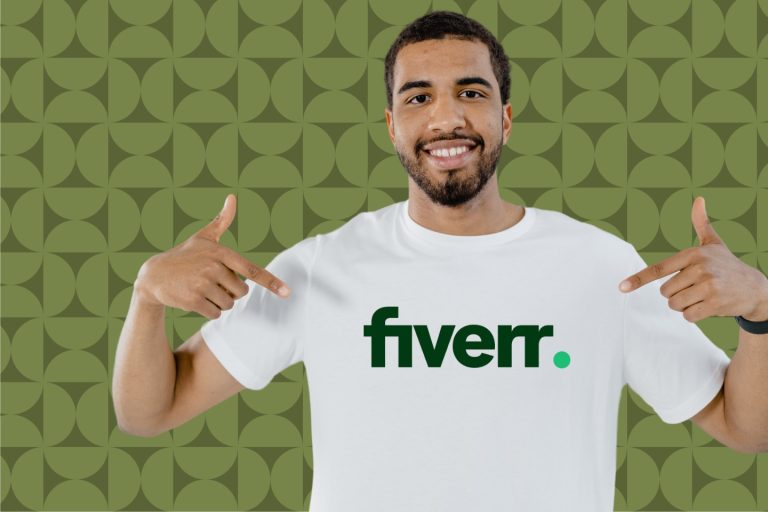 A smiling man points to the Fiverr logo on his white T-shirt, hinting at ways to make money on Fiverr. The background complements him with a green geometric pattern.